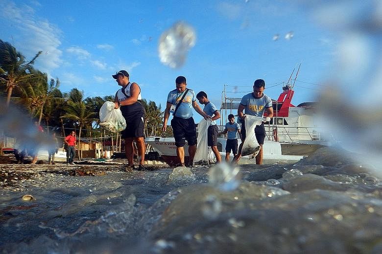 Filipino policemen and environmental advocates clearing trash on Boracay yesterday. The famous island will remain closed for six months for sanitation and development work.
