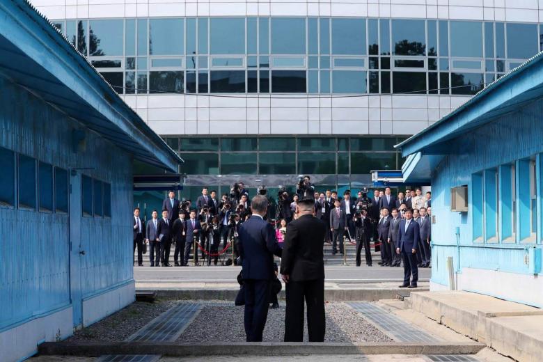 North Korea's leader Kim Jong Un (right) and South Korea's President Moon Jae In shake hands as they face the media at the Military Demarcation Line that divides their countries ahead of their summit at Panmunjom, on April 27, 2018.