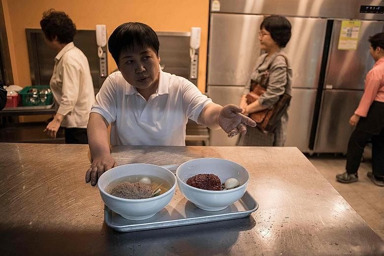 A worker preparing to serve "Pyongyang naengmyeon", a cold noodle dish, at the Nampo Myeonok noodle bar restaurant in Seoul yesterday. Demand for North Korea's signature dish peaked all over the South's capital after it was featured on the menu at th