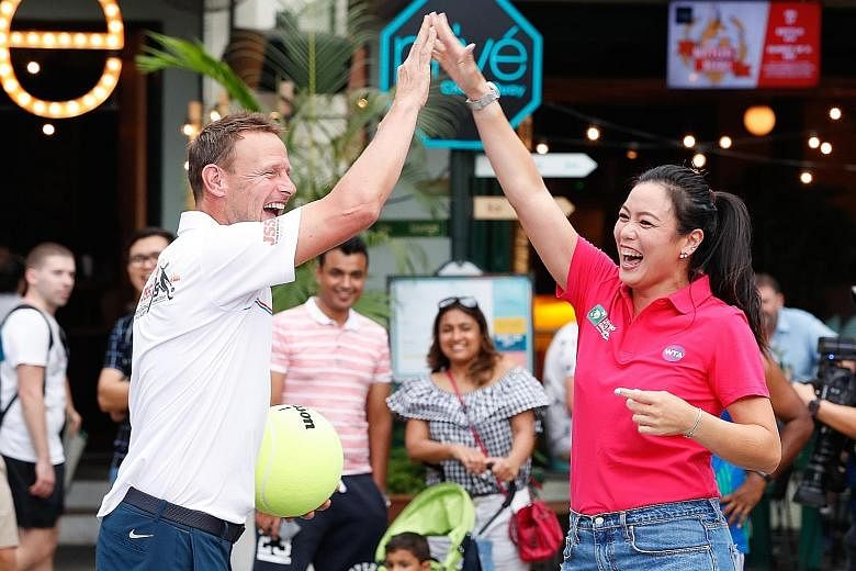 World No. 1 women's tennis doubles player Latisha Chan, high-fiving former England striker Teddy Sheringham during a cross-sports activity at Clarke Quay yesterday. Chan, 28, is in Singapore to promote the Oct 21-28 WTA Finals ahead of the ticket sal
