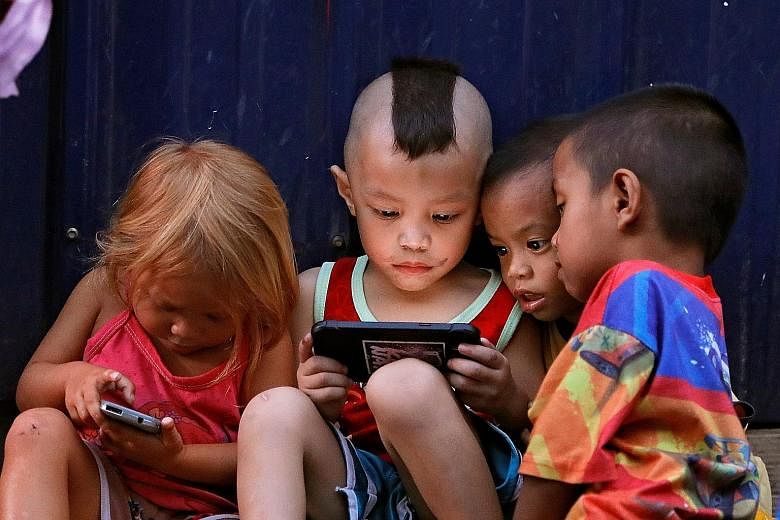 Filipino children in Cubao, Quezon City, Manila, playing games on screen devices on March 27. The use of mobile devices can cause strains from a misalignment between a student's line of sight and his hand position.