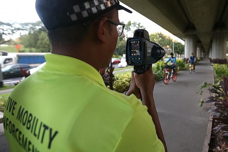 An active mobility enforcement officerusing a speed gun to spot speeding cyclists and PMD users during the enforcement blitz yesterday.