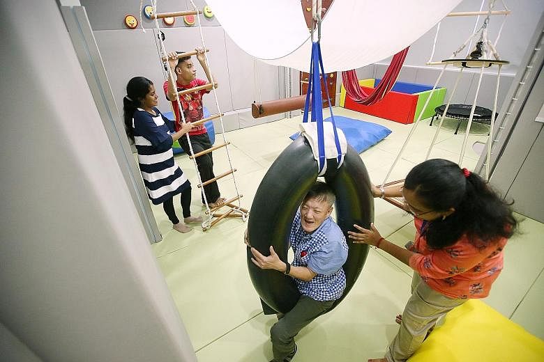 Mr Yap Koon Seng trying out the tyre swing under the watchful eye of therapist Sivasankari Neelothpalam. Far left, Muhammad Nor Hanis Azman climbing the rope ladder with the help of therapist assistant Anthonysamy Mary Kavi Nevadha.