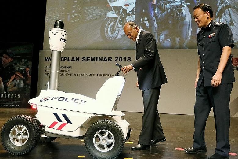Home Affairs and Law Minister K. Shanmugam, accompanied by Commissioner of Police Hoong Wee Teck, being handed a police smartphone by the S5 Pan-Tilt-Zoom Patrol Robot at the annual police workplan seminar yesterday. The robot and special smartphone 