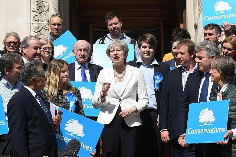 British Prime Minister Theresa May flanked by supporters outside Wandsworth Town Hall in London yesterday after the Conservative Party retained control of the council in local elections.