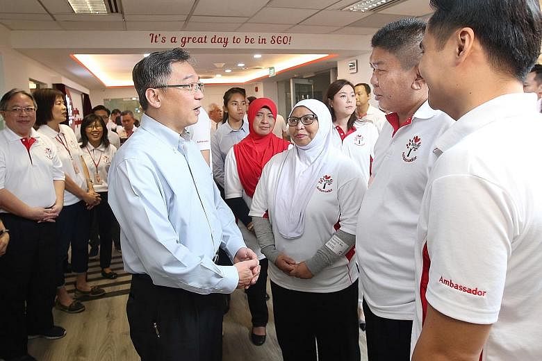 Health Minister Gan Kim Yong chatting with Madam Noraisah Yacob (third from right) and other volunteers at the official launch of the new Silver Generation Office training facility yesterday.