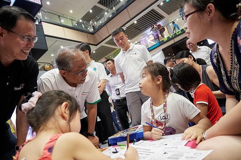Environment and Water Resources Minister Masagos Zulkifli and North West District Mayor Teo Ho Pin (far left) chatting with Yishun resident Charlene Ng, seven, at the Energy-Saving Challenge launch.