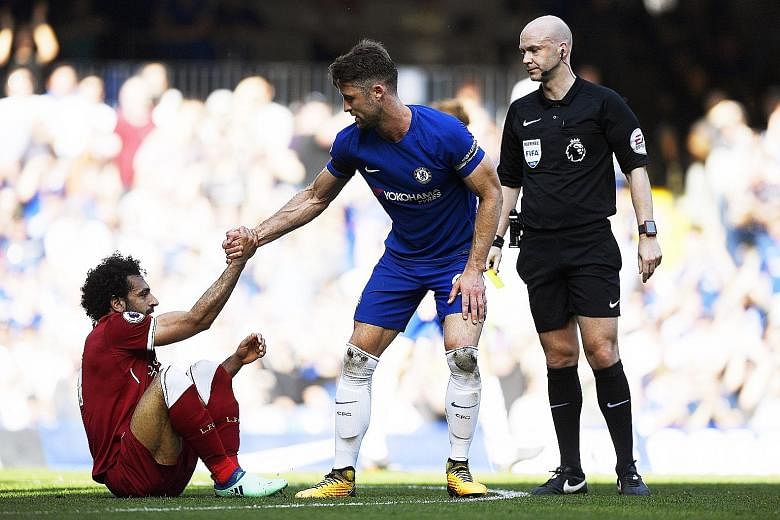 Chelsea captain Gary Cahill helping Mohamed Salah get to his feet, as referee Anthony Taylor, with yellow card in hand, is ready to caution the Reds' top scorer for simulation during the English Premier League match at Stamford Bridge on Sunday.