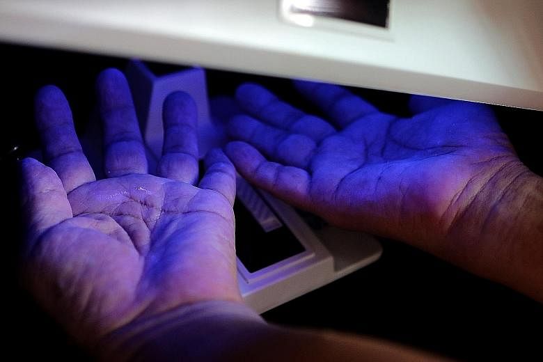 Applying a handrub with special fluorescent dye, participants could find out whether their hand-washing was up to the mark by placing their hands under ultraviolet light. Shoppers and hawkers at Yuhua Village Market in Jurong East learning the proper