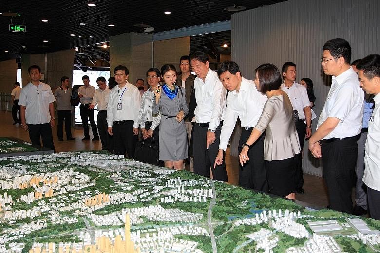 Deputy Prime Minister Teo Chee Hean and then Minister for Social and Family Development Chan being briefed on the Raffles City Chongqing project during a visit to China in July 2014. Mr Chan giving out red packets to some 130 senior citizens at a Chi