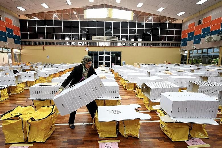 A worker making final preparations yesterday at a counting centre in Klang, Selangor, before today's vote. Pollsters say neither BN nor PH has secured a comfortable lead.