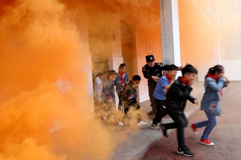 Primary school pupils taking part in an anti-terrorism drill in Huaibei, Anhui province, on Monday, aided by a police officer. Since March 2015, after a series of violent mass attacks took place in China, parts of the country have begun conducting su