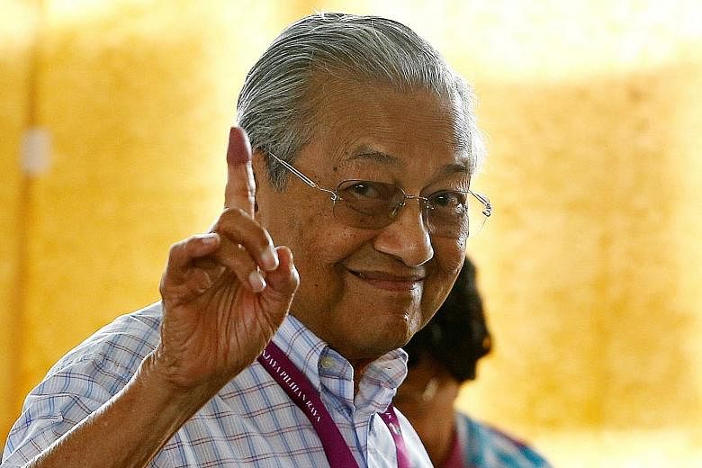 Above: Tun Dr Mahathir Mohamad, leader of Pakatan Harapan, holding up an ink-stained finger as he voted in Alor Setar yesterday. The former prime minister had criss-crossed the country, campaigning relentlessly for the opposition for this election. L