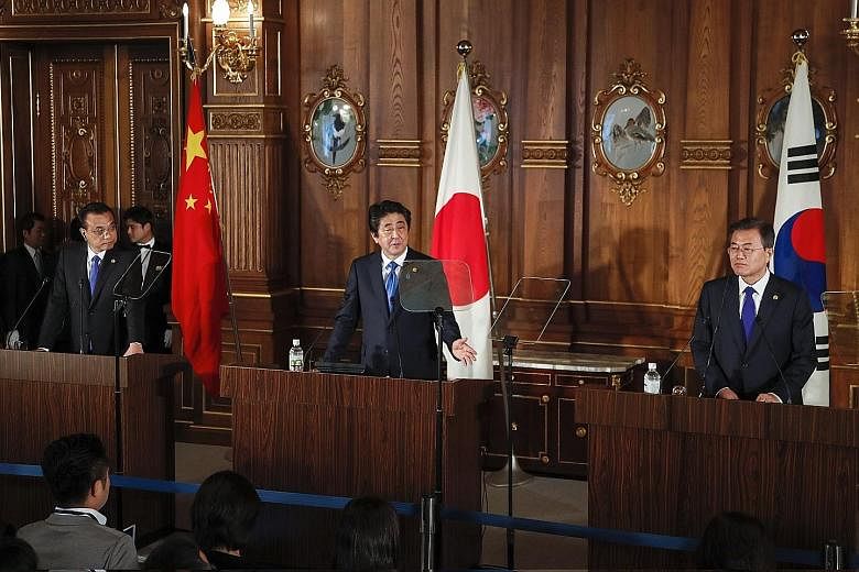 From far left: Chinese Premier Li Keqiang, Japanese Prime Minister Shinzo Abe and South Korean President Moon Jae In at a news conference after holding talks in Tokyo yesterday. The three leaders stuck largely to broad strokes without diving into the