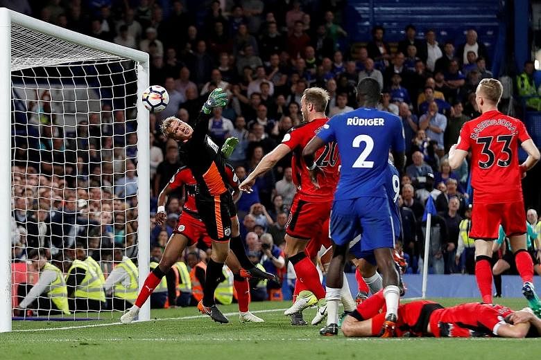 Huddersfield goalkeeper Jonas Lossl makes a survival-sealing save during the 1-1 draw against Chelsea on Wednesday. The Dane tipped Andreas Christensen's (not pictured) header onto the post in the 83rd minute.