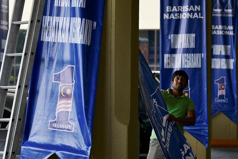 A worker removing a Barisan Nasional banner in Kuala Lumpur yesterday. Eight of the 12 elections to state assemblies on Wednesday yielded clear winners, and as of last night, three menteris besar had been formally named - in Kelantan, Terengganu and 