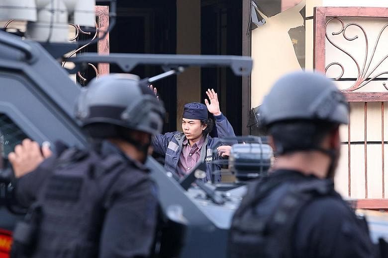 Top: An inmate surrendering to police after the prison riot in Kelapa Dua, 25km from Jakarta's city centre. Above: Firearms, ammunition and bulletproof gear used by the prisoners.