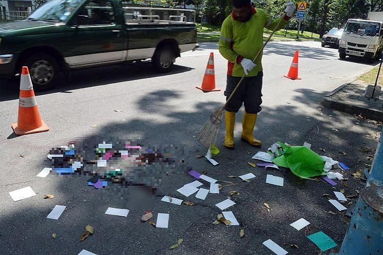A worker clearing up at the scene of the fatal accident last Aug 25. Galistan Aidan Glyn had mounted the kerb and collided into Ms Serene Ng, who had just crossed the road and was standing on the grass patch next to the kerb. Ms Ng died later that da