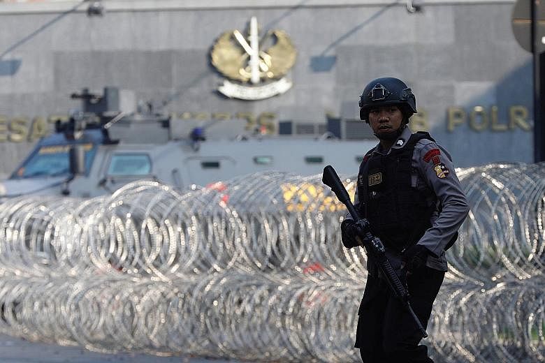Jemaah Ansharut Daulah founder Aman Abdurrahman was among the inmates at the jail. A policeman patrolling near an armoured vehicle at the Mobile Police Brigade headquarters in Depok, Indonesia, on Thursday.