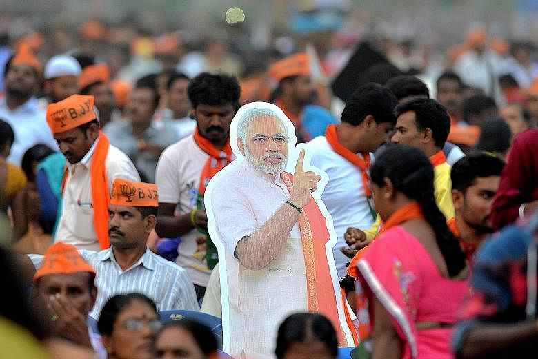 BJP supporters, with a cut-out of Prime Minister Narendra Modi, at a rally in Bangalore, near Karnataka, last week. Above: Congress president Rahul Gandhi in Malur, Karnataka, on Monday.