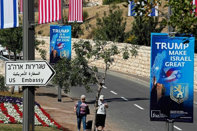Passers-by near the new United States embassy in Jerusalem, as banners praising President Donald Trump hang from lamp posts along the streets.