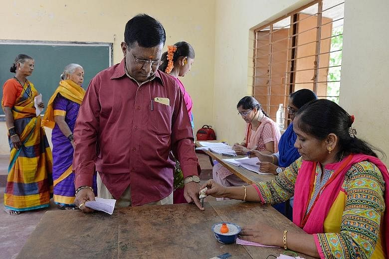 An election official putting indelible ink on a voter's finger at a polling station in Bangalore yesterday.