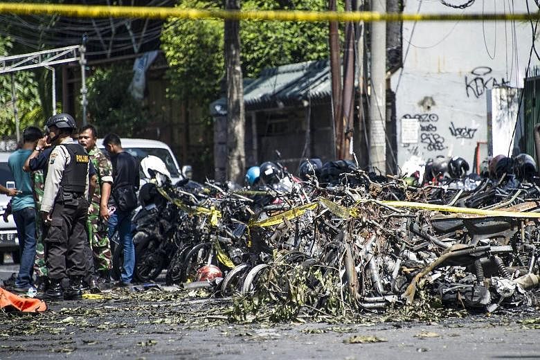 Police and soldiers examining the area after an attack outside the Surabaya Centre Pentecostal Church in East Java yesterday. The attack was one of three carried out by a family on churches in Surabaya. Puji Kuswati, 46, and her family, including her