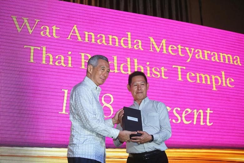 Mr Lim Keng Boon (at right) receiving a long service award yesterday from Prime Minister Lee Hsien Loong at a celebration marking the Wat Ananda Metyarama Thai Buddhist Temple's 100th anniversary.