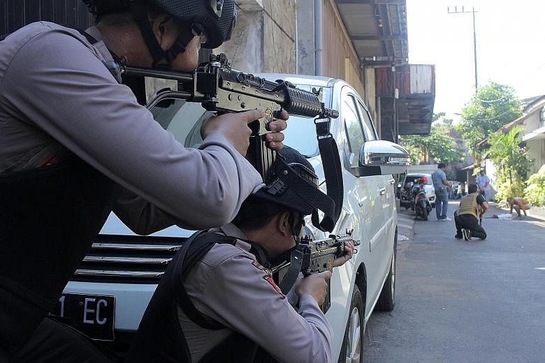 Police providing cover as fellow officers search a man after the blast at the police headquarters in Surabaya. There is now an unprecedented willingness by ISIS to contemplate deploying women as terrorists, according to one study.