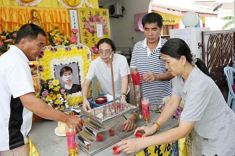 (From left) Corporal Kok Yuen Chin's uncle Kok Min Kweh, aunt Helen Kok, father Kok Meng Hwa and mother Wong Siew Fong at his wake in his parents' home in Melaka yesterday. The 22-year-old, who died on Sunday during celebrations for his ORD, was foun