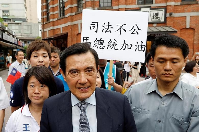 A Kuomintang member holding a placard reading, "Injustice, President Ma cheer up" yesterday as former president Ma Ying-jeou leaves an event in Taipei. The High Court overturned a lower court's not-guilty ruling and sentenced Ma to four months' jail 