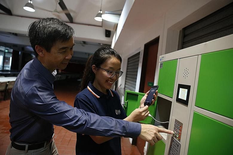 (Far left) Dr Zhang Jingxin blending the food before it goes into the anaerobic digester. (Left) Prof Tong Yen Wah shows student Gu Danning how the food-waste powered charging station in NUS' Raffles Hall works.