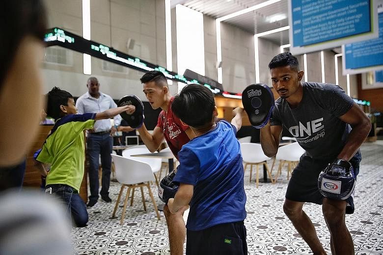 One Championship MMA exponents Christian Lee and Amir Khan giving underprivileged children from Fei Yue Centre a workshop on punching and kicking at the SGX Centre yesterday. SGX announced One Championship as the official fitness partner for this yea