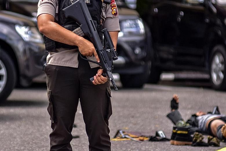 Top: An Indonesian police officer standing guard next to the body of a suspected attacker. Above: Indonesian police officers helping an injured colleague following the attack at the Pekanbaru police station by men using samurai swords. An Indonesian 
