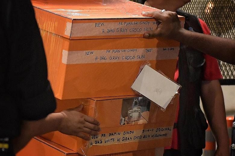 The police carted away bags filled with jewellery, cash, watches and other valuables, while many of the orange boxes were labelled with pictures and descriptions of different Hermes Birkin bags. Malaysian police removing items in a raid on Thursday n