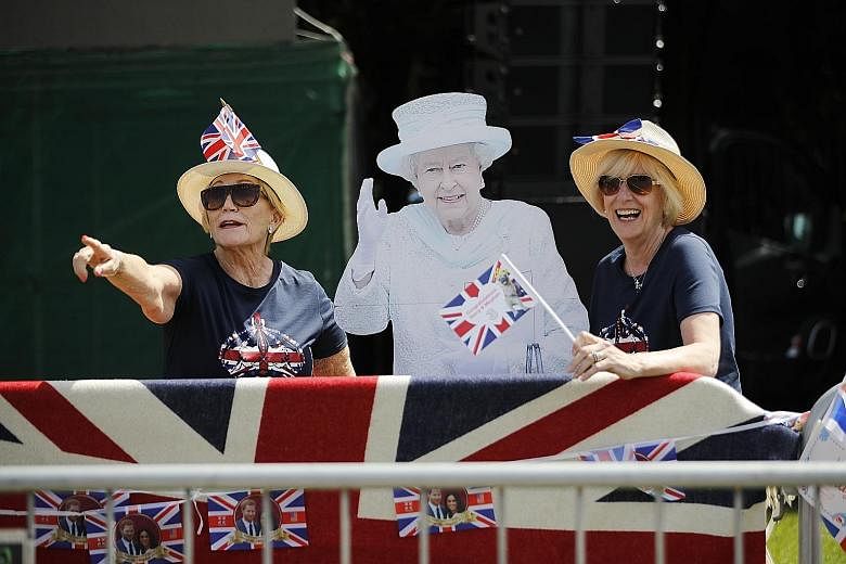 Far left: Police officers patrolling the streets. More than 100,000 members of the public are expected to turn up. Left: Businesses continue to cash in, with novelty items such as this drink, the "Megharryccino". Above: Fans with a cut-out of Queen E