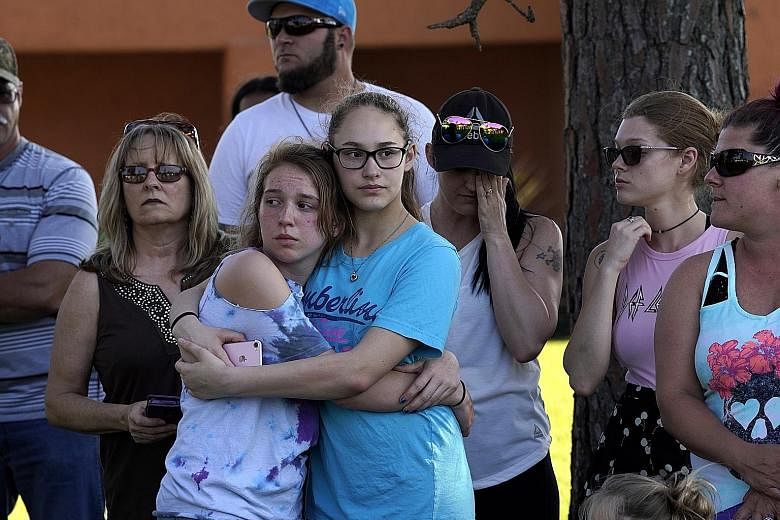 Those shocked by the shooting comforting each other at a vigil outside Santa Fe High School. The suspect, 17-year-old Dimitrios Pagourtzis (far left), surrendered and was taken into custody. He is being held on capital murder charges.