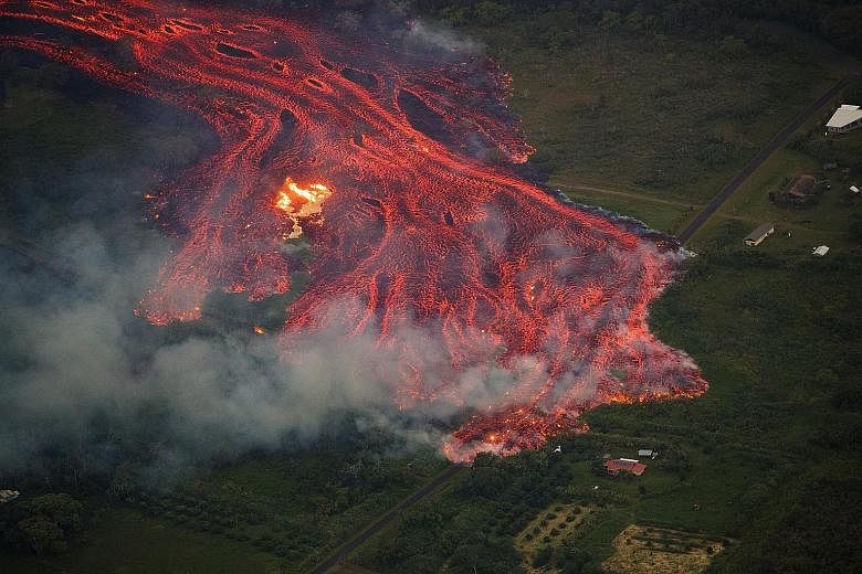 An aerial view of a massive flow of fast-moving lava consuming everything in its path. The remnants of one home (left) can be seen burning on Saturday while the lava approaches another home in Pahoa, Hawaii.