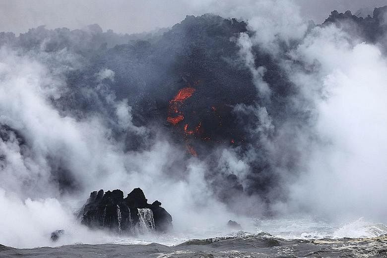 A steam plume rising as lava (centre) enters the Pacific Ocean, after flowing to the water from a Kilauea volcano fissure, on Hawaii's Big Island on Sunday. Officials are concerned that "laze", a potentially dangerous product formed when hot lava hit
