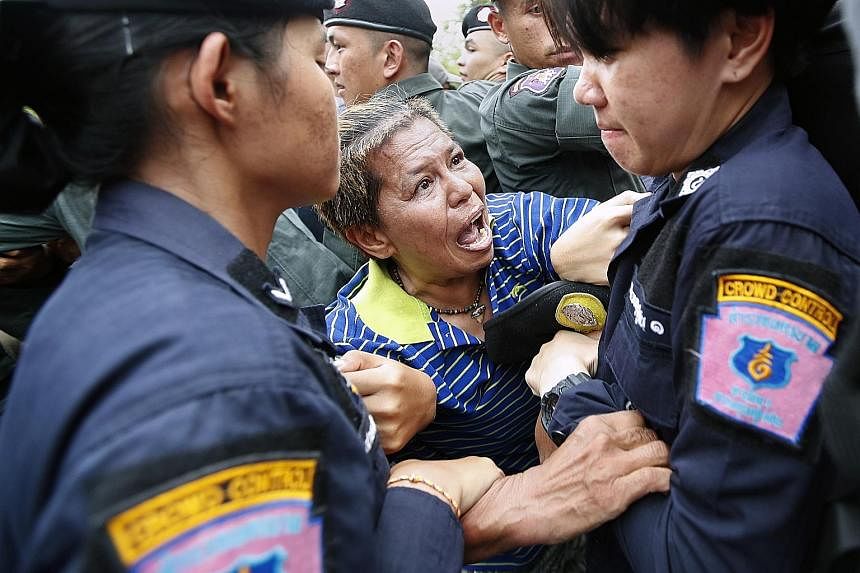 A protester being arrested by police near Government House in Bangkok yesterday. The group behind the march is calling for polls later this year, after the military government had repeatedly pushed back the general election after initially promising 
