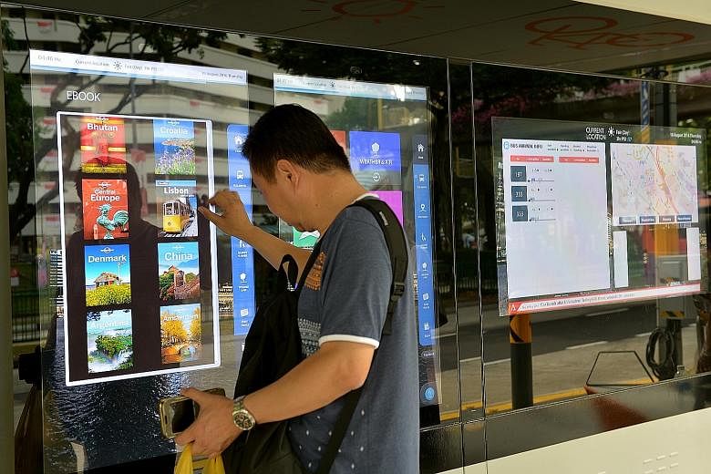 A commuter checking out interactive "smart boards" at a bus stop. Such boards offer information such as bus timings, the weather and street directory. There are physical books to browse, as well as e-books to download too. Commuters can also use mobi
