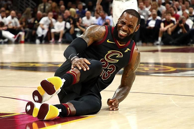 LeBron James of the Cleveland Cavaliers played a pivotal role in his side's 109-99 win against the Boston Celtics on Friday, despite a moment (above) when he went down, clutching his knee in pain.