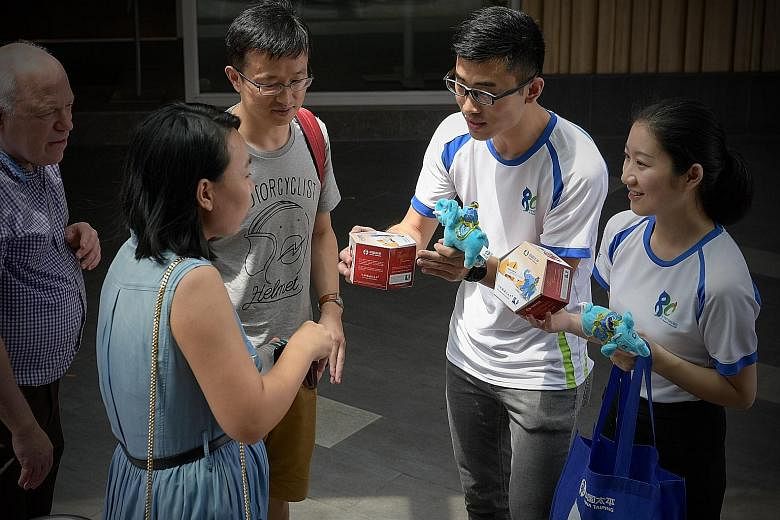 China Taiping Insurance Singapore staff selling fortune cookies and elephant plushies at Chinatown Point yesterday to help raise funds for The Straits Times School Pocket Money Fund. The street sales will continue today.