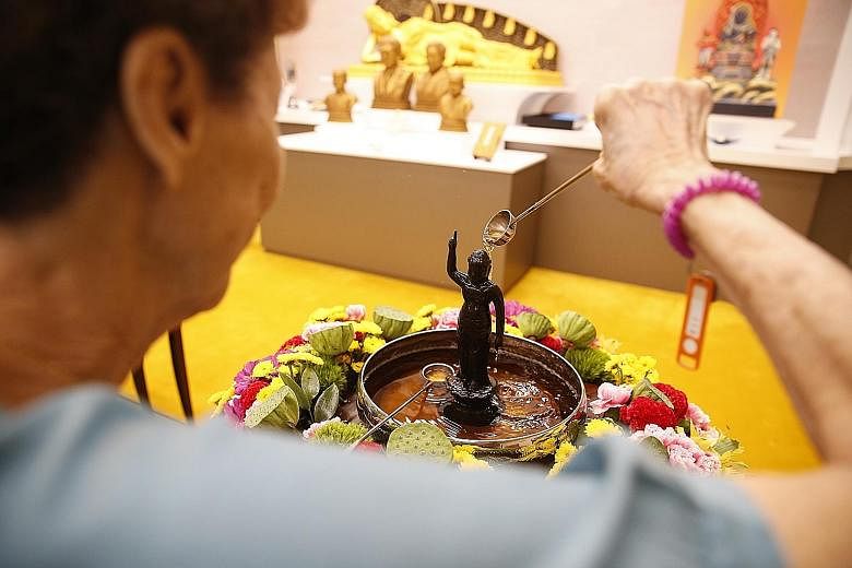Devotees mark Vesak Day in different ways around the island. From left: At Thekchen Choling, Singapore's only 24-hour Tibetan Buddhist temple, a devotee spins the Giant Mani Wheel for purification while other devotees practise the offering of robes o