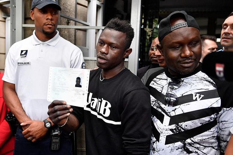 Malian migrant Mamoudou Gassama holding his temporary French residence permit yesterday. With him is his older brother.