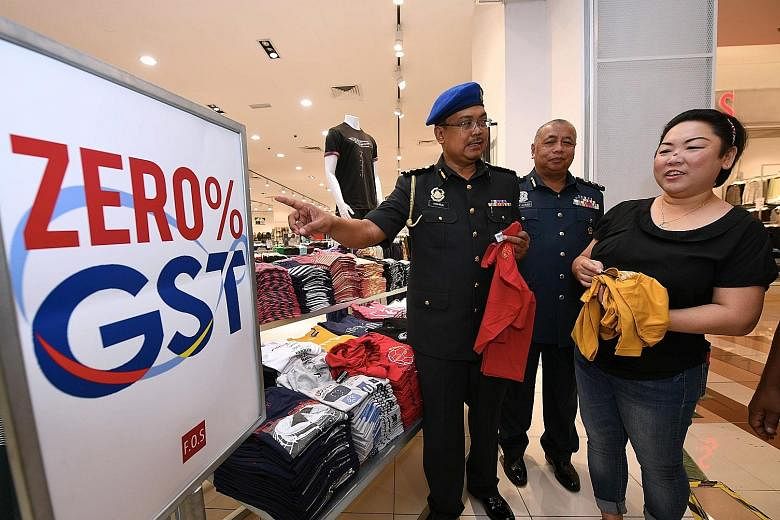 Officers from the Domestic Trade, Cooperatives and Consumerism Ministry in Johor state checking on a business outlet yesterday. Malaysia's unpopular 6 per cent GST was zero rated by the new Mahathir Mohamad administration to fulfil an election promis