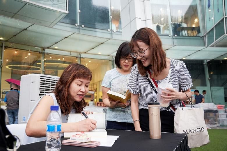 Ms Lorna Tan signing books (above) at the session on May 26, where she spoke on financial and retirement planning. 