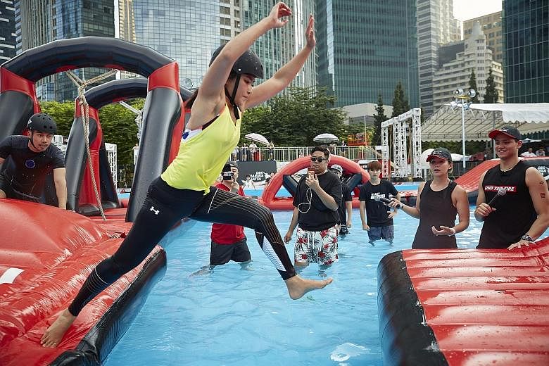 Team Under Armour's Sophie Mong in the DBS Marina Regatta's Battle Bay Extreme Celebrity Challenge yesterday, watched by opponent and Olympic champion Joseph Schooling (far right). The swimmer, together with sailors Griselda Khng and Olivia Chen, eac