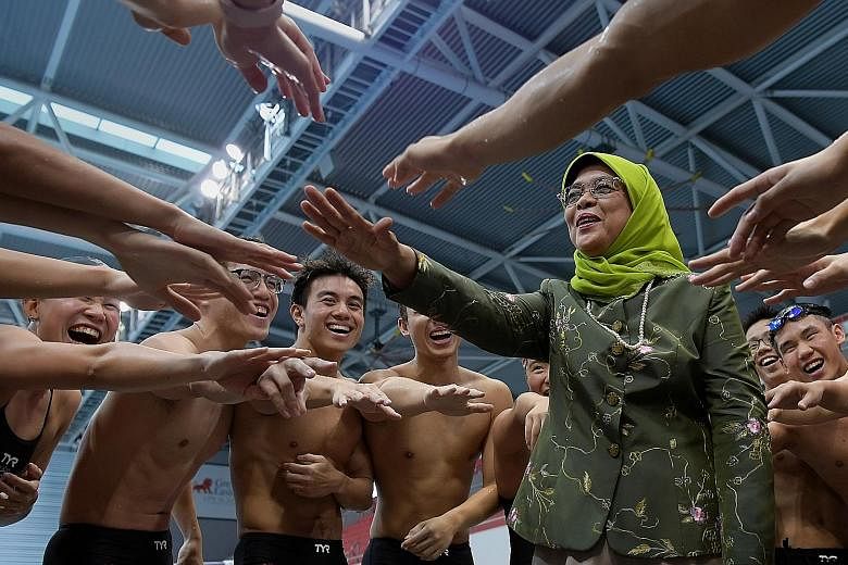 President Halimah Yacob taking part in a cheer with Team Singapore swimmers at the OCBC Aquatic Centre yesterday. President Halimah paid a visit to Team Singapore athletes from swimming - including Olympic champion Joseph Schooling - boccia, pencak s