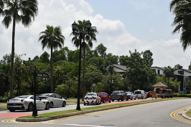 Additional security cameras were seen being put up on Sentosa ahead of the summit. A queue of cars (above) in Sentosa Cove yesterday amid heightened security. At Capella hotel (right), security staff were stationed at the entrance to screen visitors.